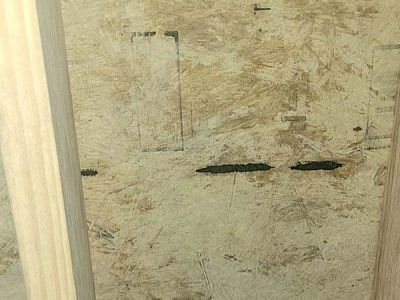 Beige particleboard with wood studs on the sides, visible markings and dark streaks.