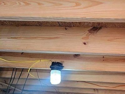 Lightbulb hanging from wooden beams, with exposed wiring.