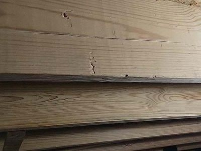 Close-up of light-colored wood planks with a crack, stacked horizontally.