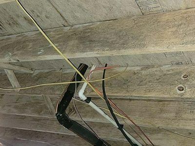 Wooden ceiling with exposed wires and pipes.