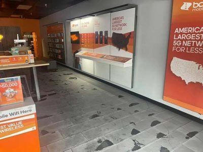 Interior of a Boost Mobile store. Orange and white signage, dark footprints on gray tile floor.