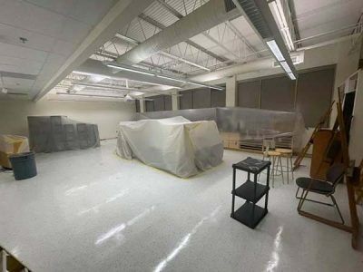 An empty art studio with white floor and covered furniture, ready for use.