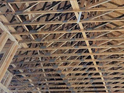 Wooden roof trusses in an unfinished building, with metal connectors and exposed beams.