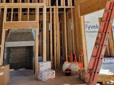 Interior of a building under construction, showing wooden frames, insulation, a ladder, and construction materials.