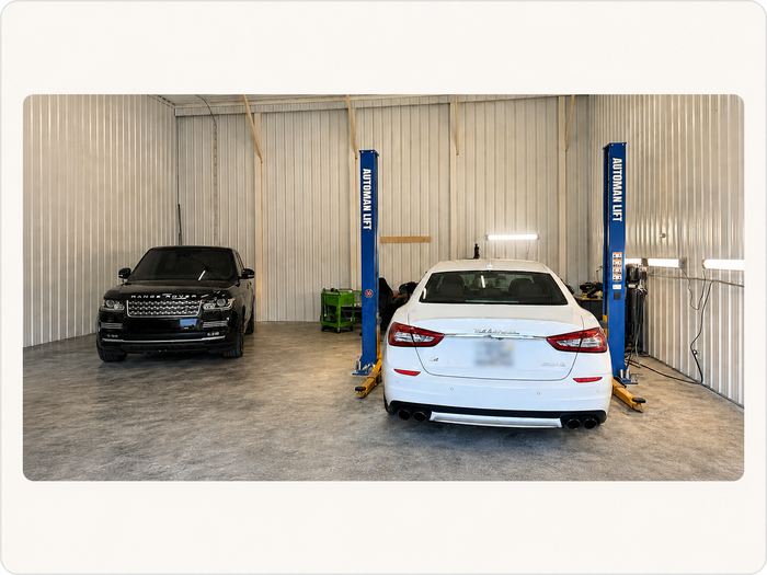 Black SUV and white sedan on vehicle lifts inside the Leon D 87 auto repair shop in Elkhart, Indiana