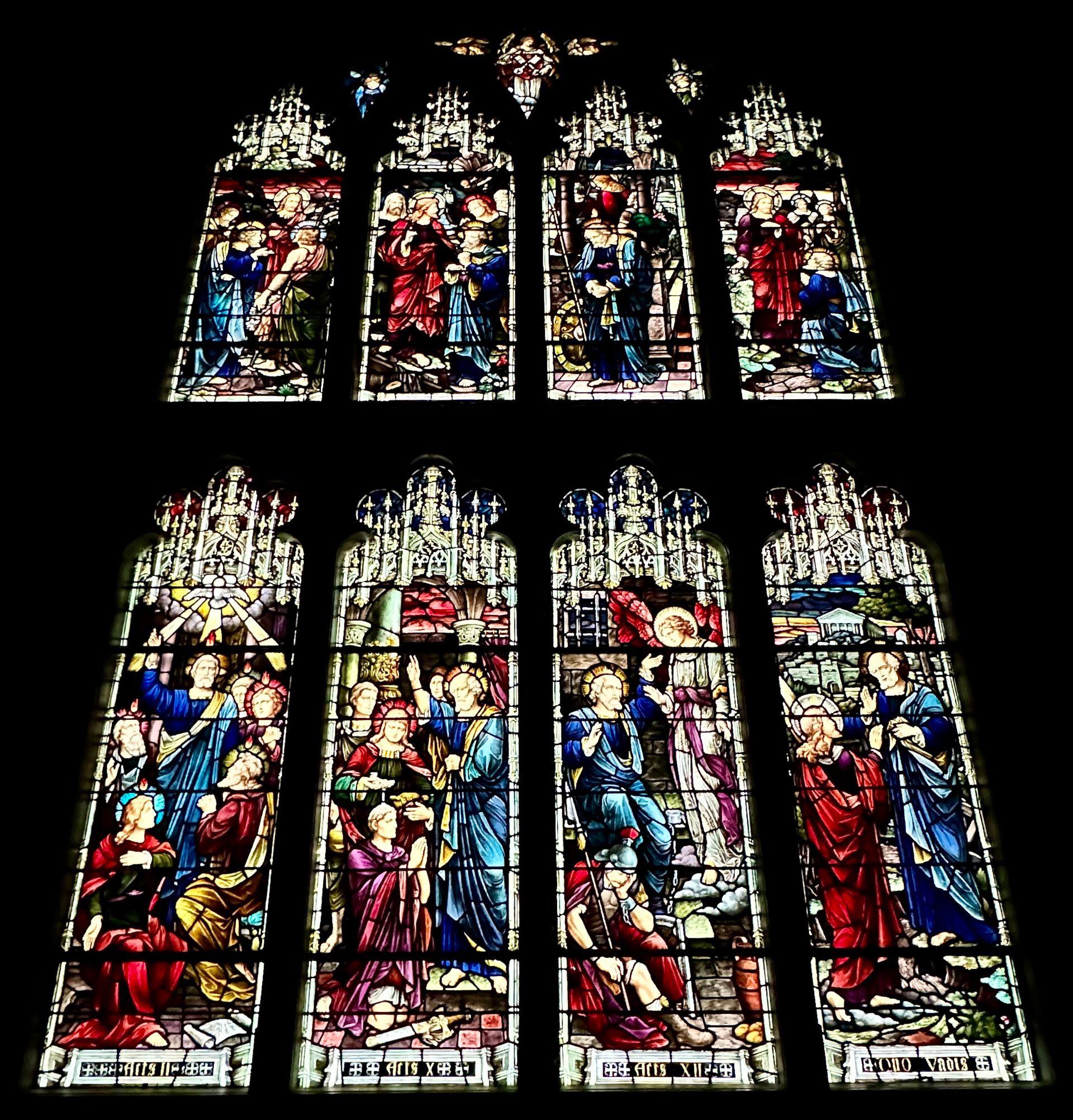 Stained glass window depicting religious scenes, vibrant colors, figures in period clothing, church setting.