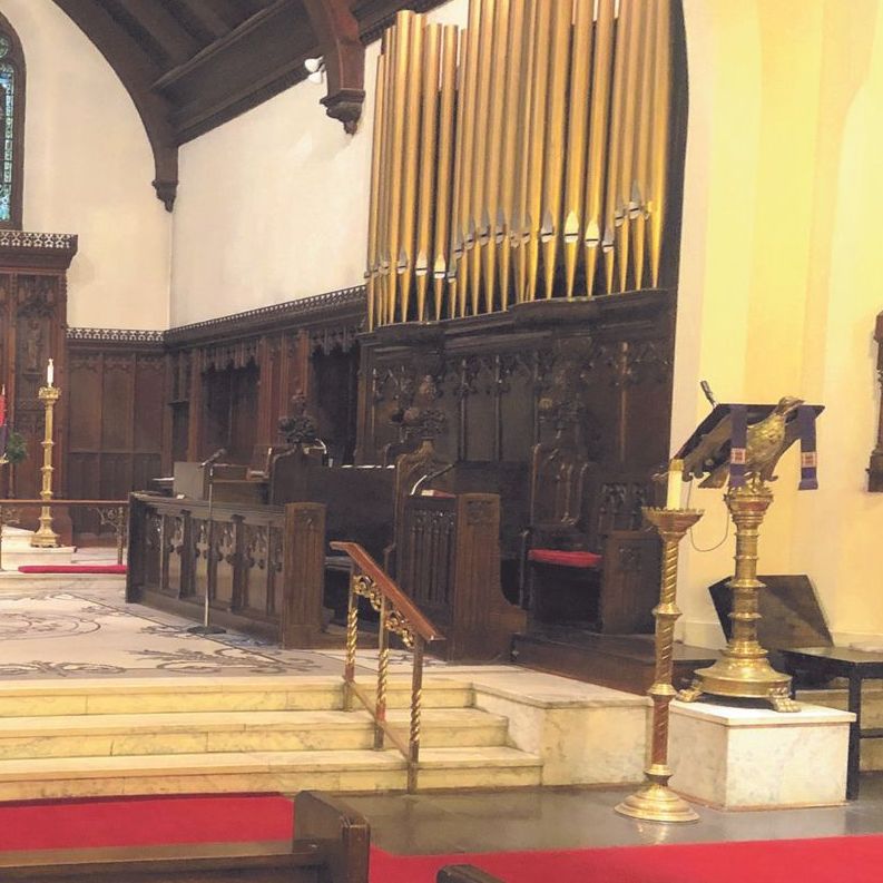 Interior of a church with organ pipes, wooden pews, and a lectern.