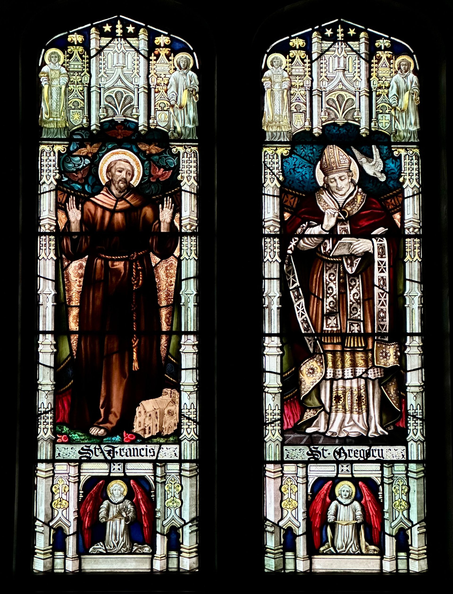 Stained glass windows: St. Francis with lamb; St. Gregory with dove. Colorful, within a church setting.