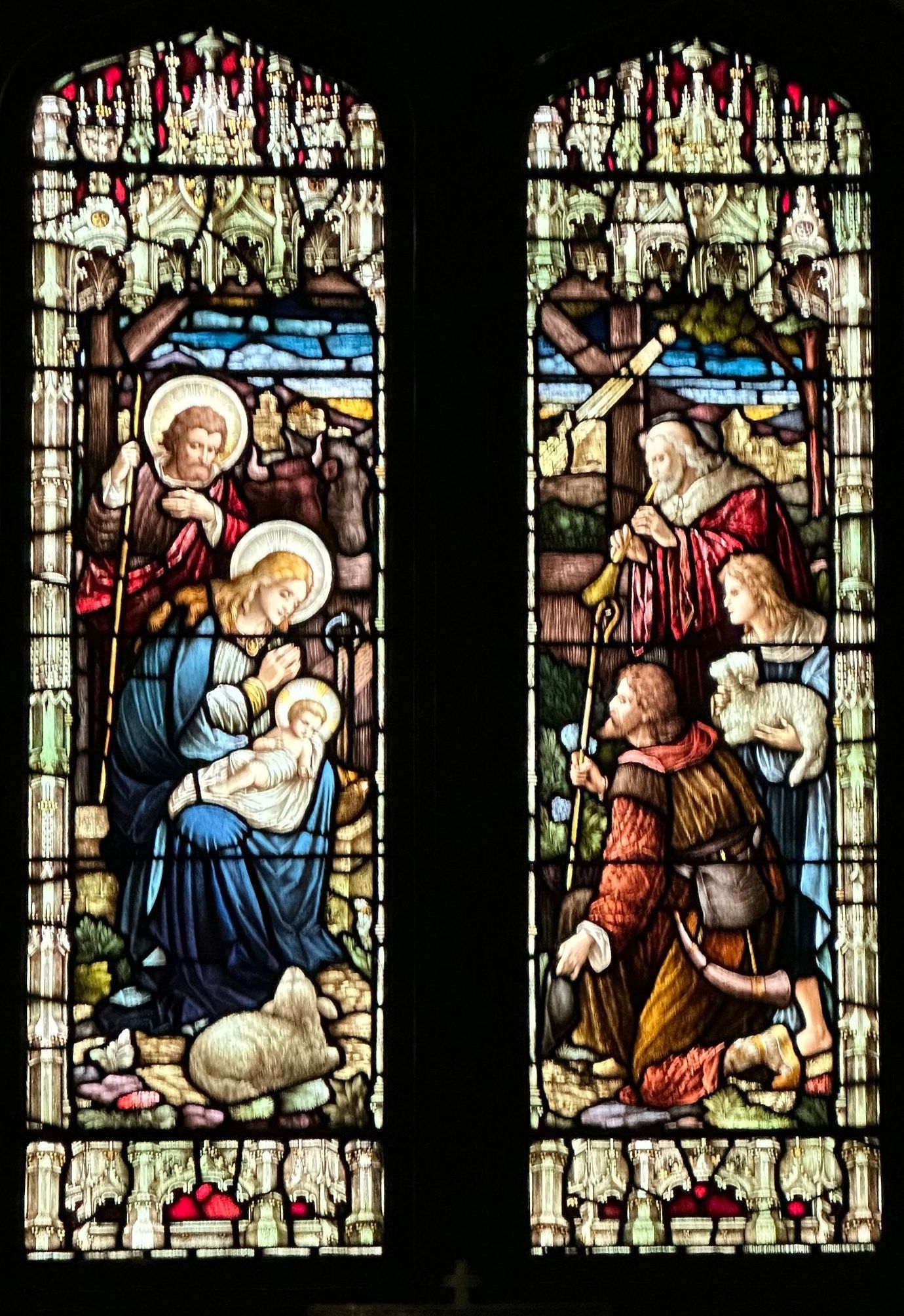 Stained glass window depicting the Nativity: Mary and Joseph with baby Jesus; shepherds kneeling.