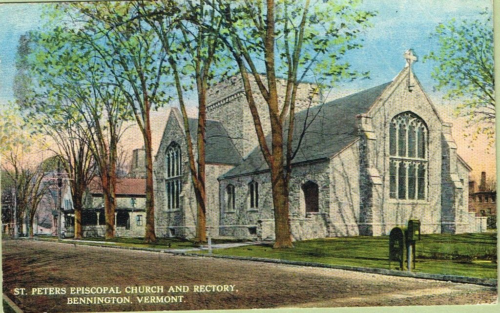St. Peter's Memorial Church and rectory in Bennington, Vermont. Gray stone building with trees, grass, and a cross.