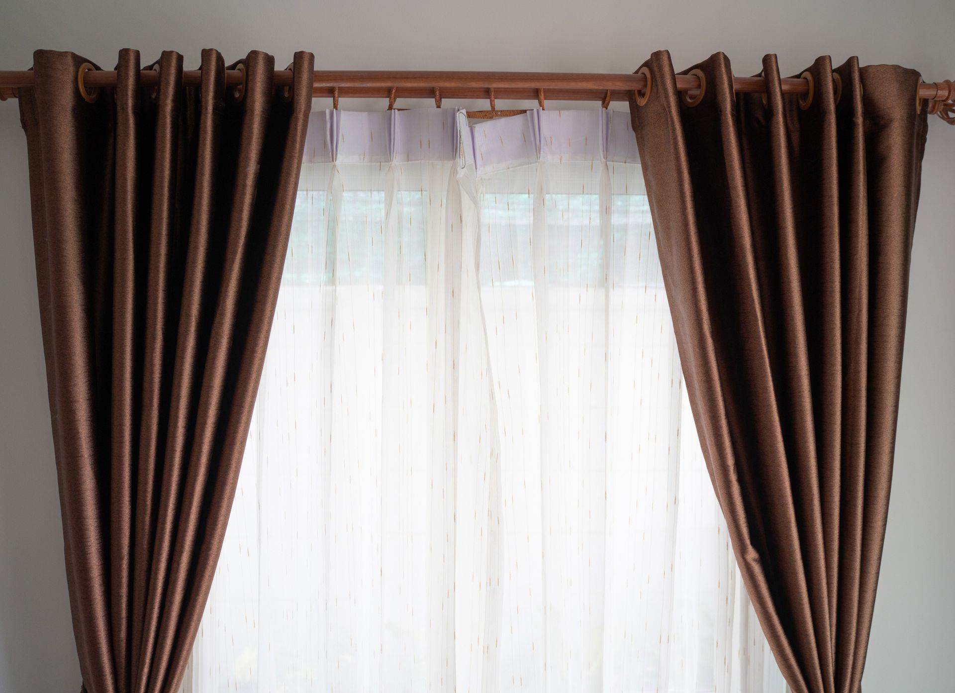 A pair of brown curtains are hanging on a window.