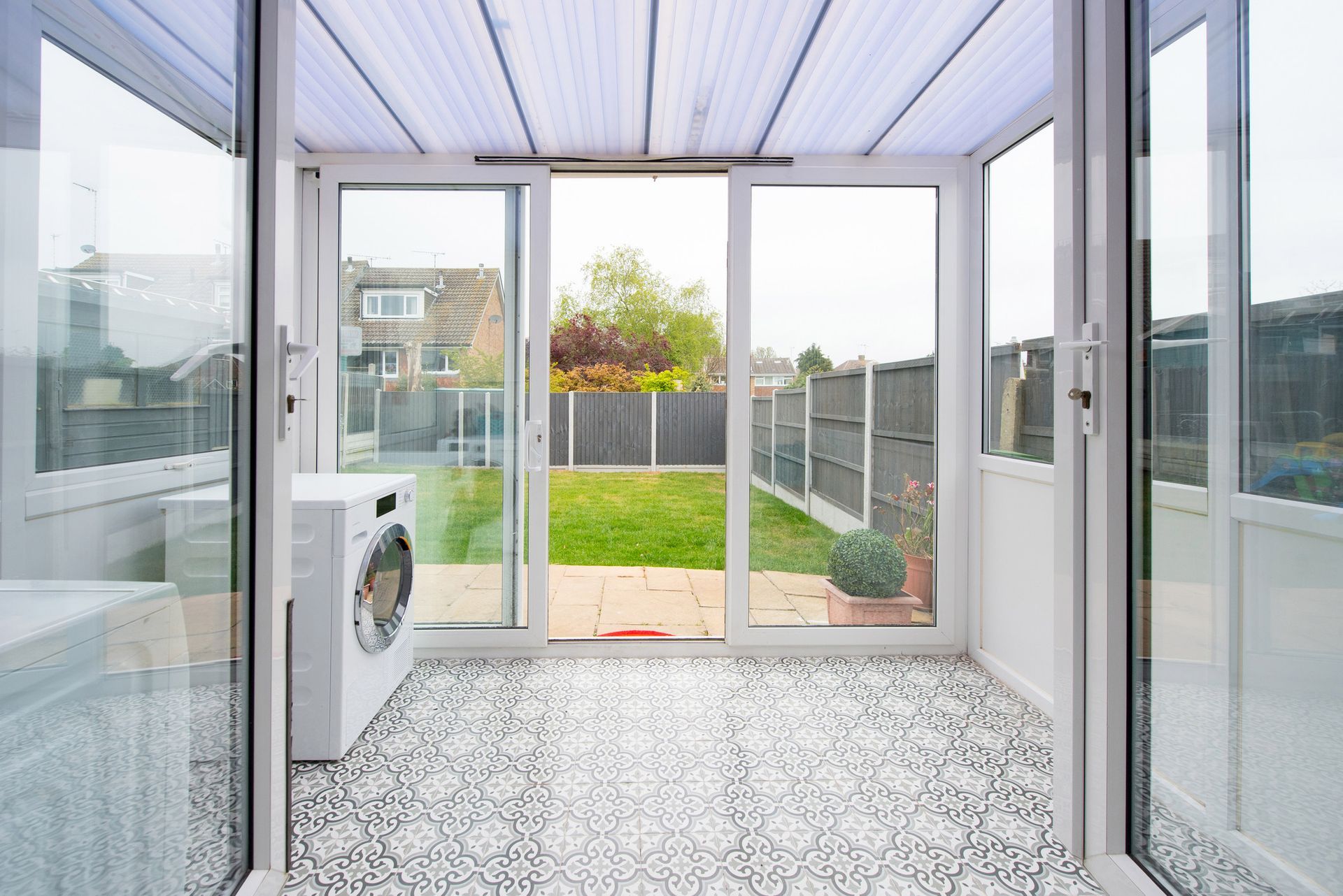 A laundry room with a washing machine and sliding glass doors leading to a backyard.