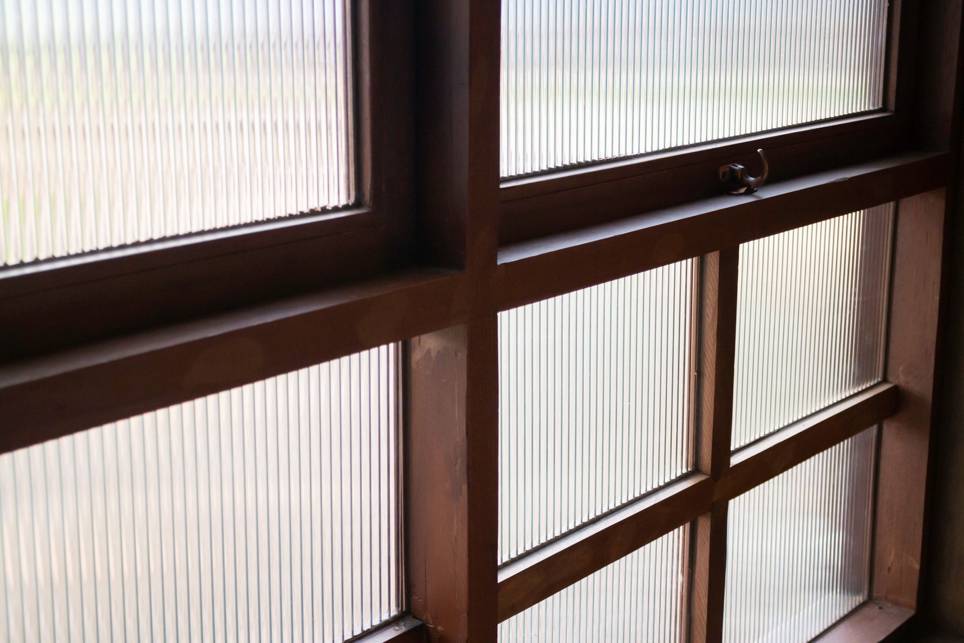 A close up of a window with a wooden frame and clear glass.