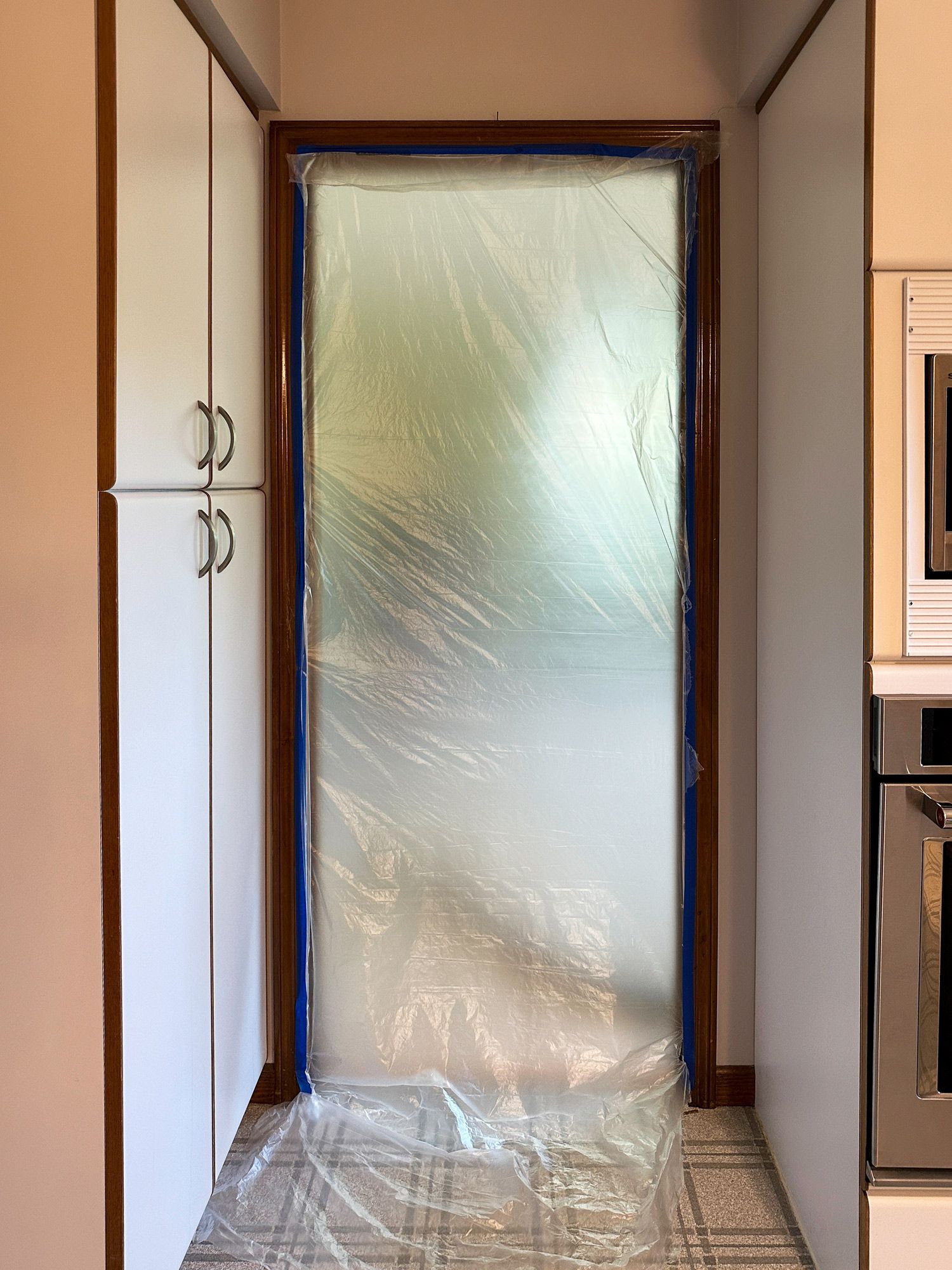 A kitchen with a door that is covered in plastic.
