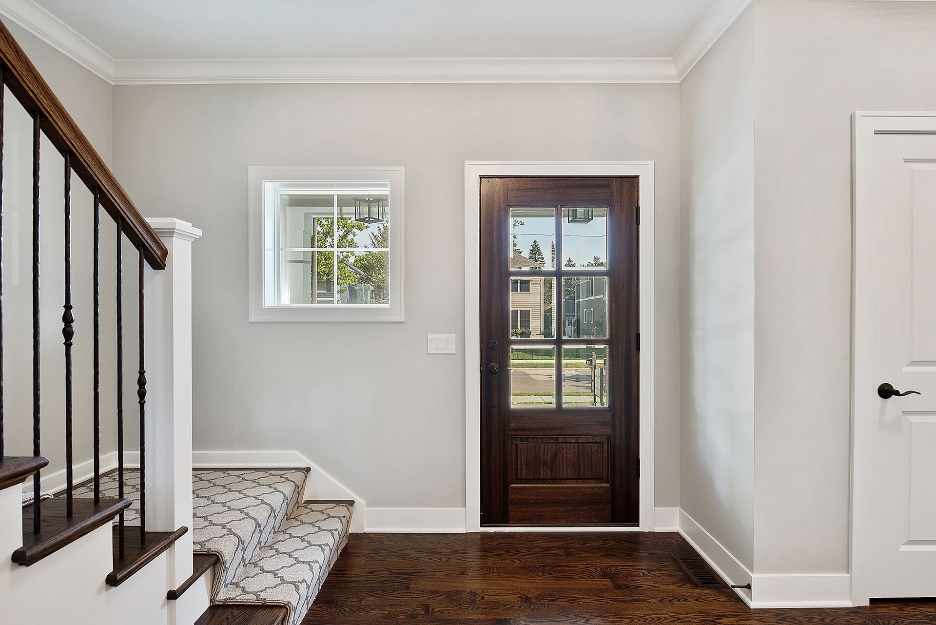 A hallway with a white door and a potted plant on a table.