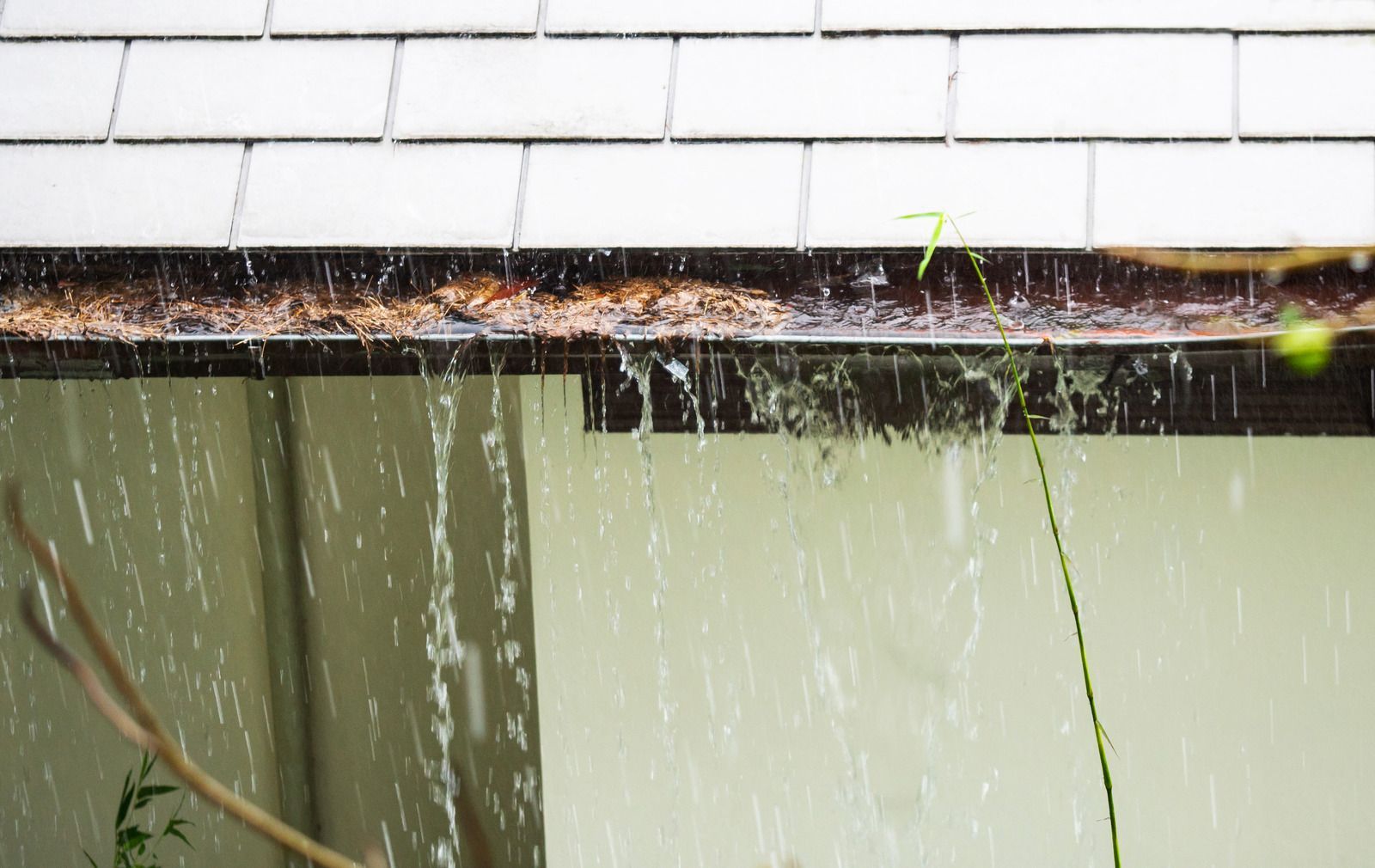 Rainwater falling from a roof into a gutter below