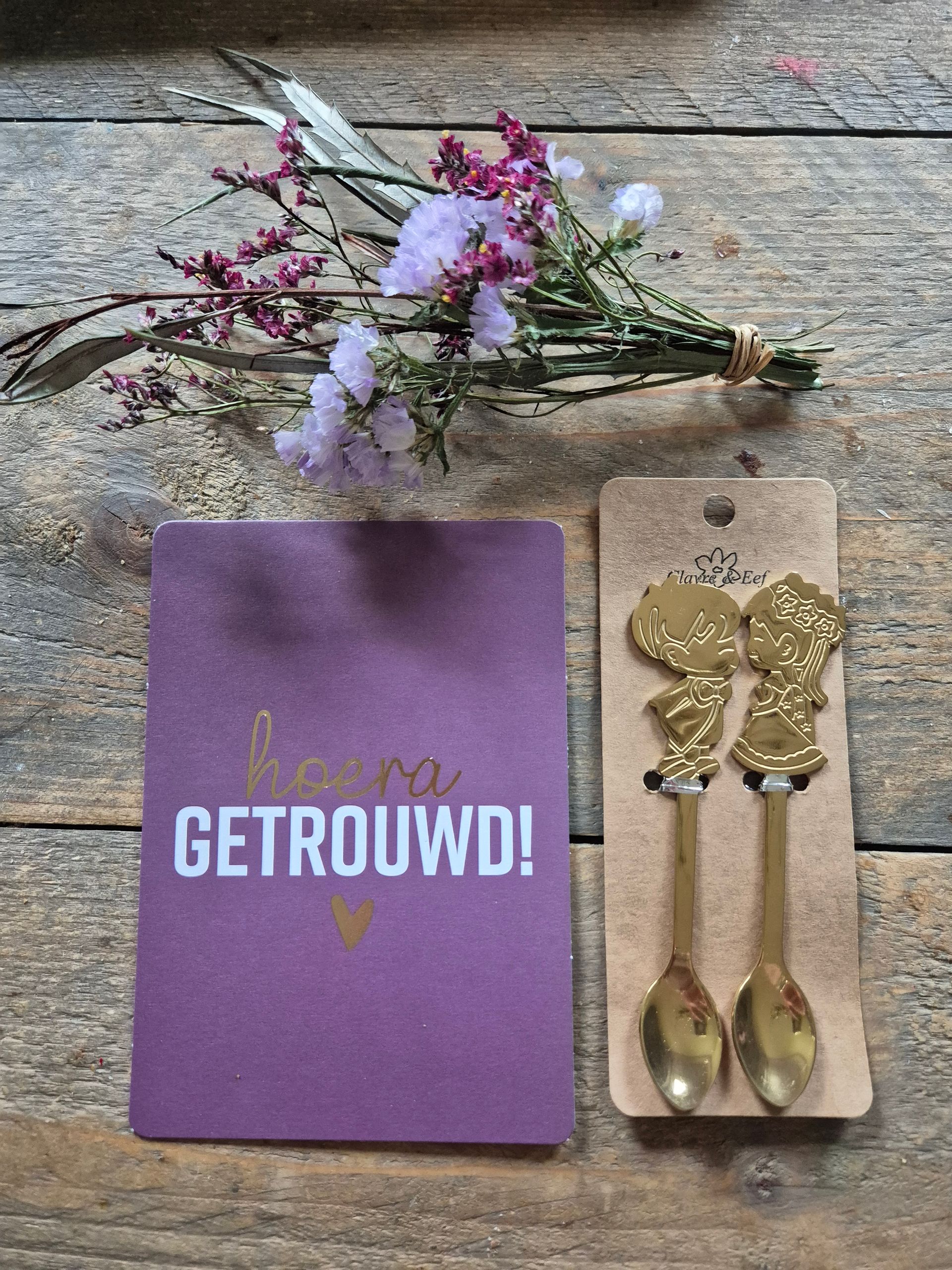 Cadeauverpakking met gouden lepels, bloemen en een paarse kaart met de tekst