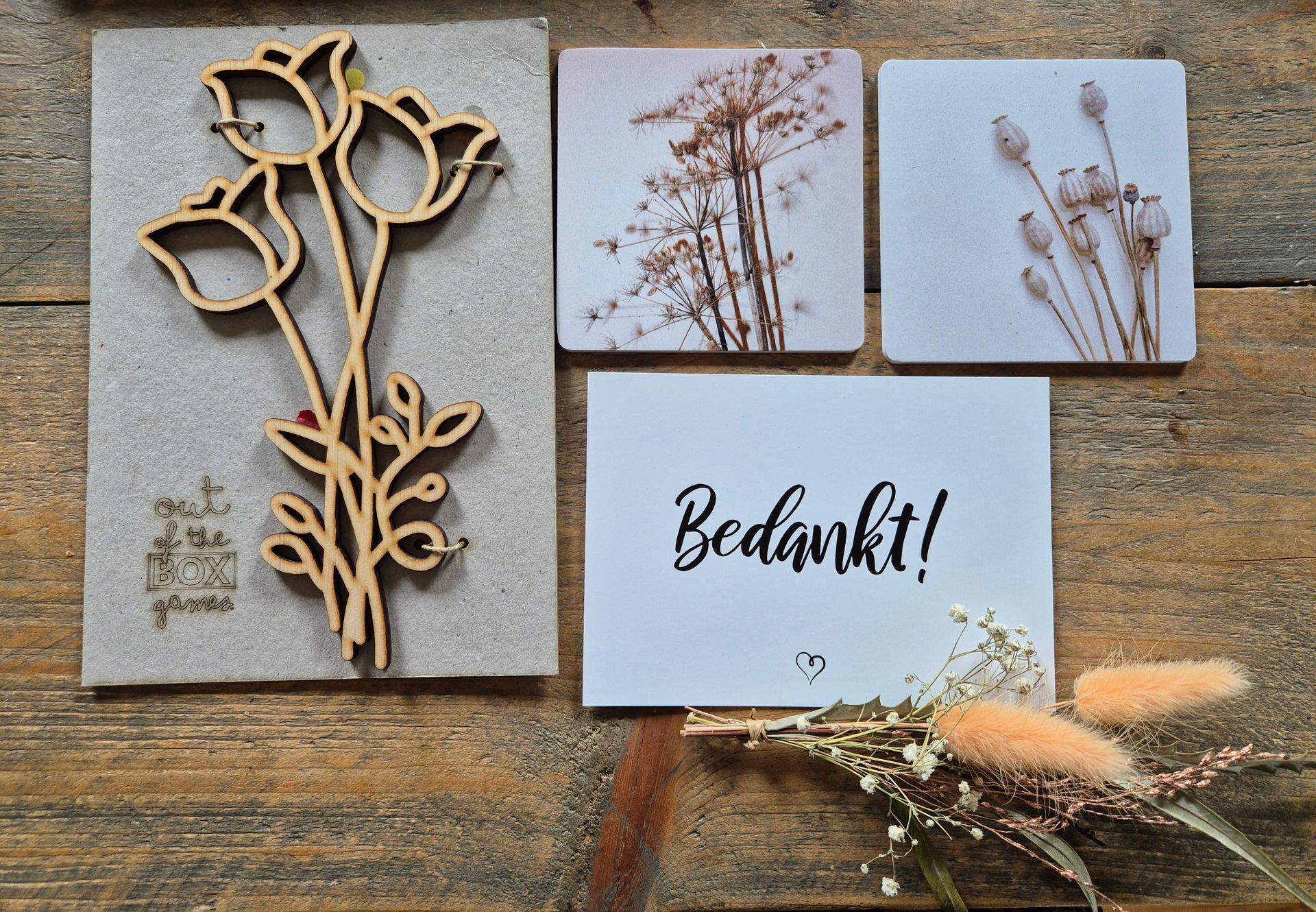 Handgemaakte bedankkaart met gedroogde bloemen en bloemmotieven op een rustieke houten tafel.