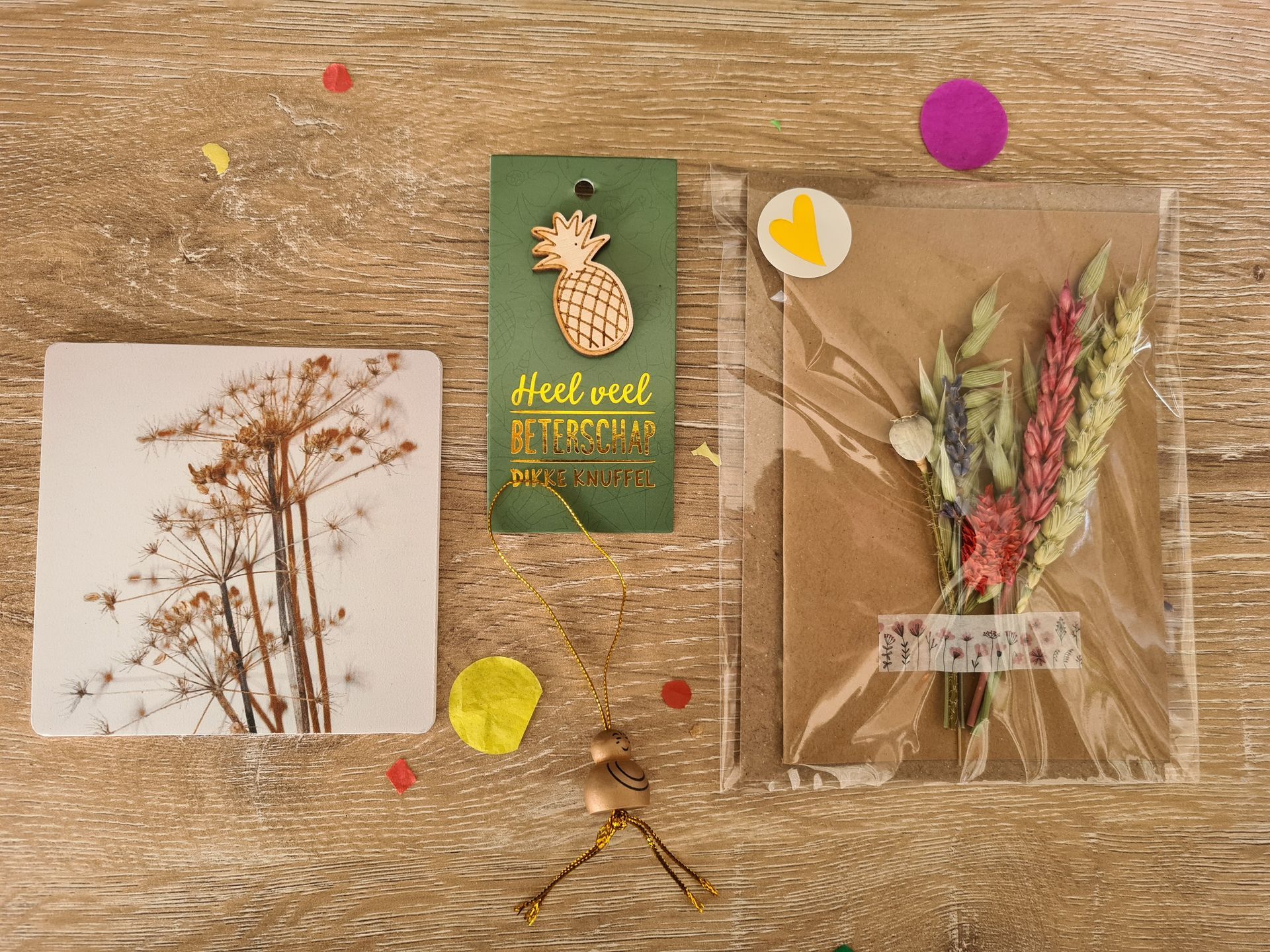 Handgemaakte wenskaart met gedroogde bloemen, gouden accenten en een klein label op een achtergrond van kraftpapier.