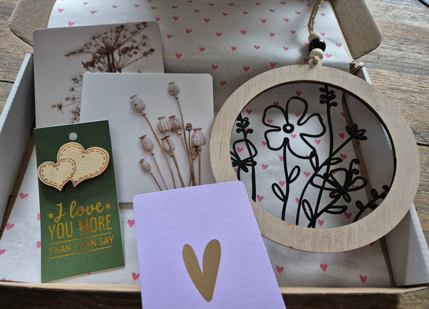 Cadeauverpakking met een bloemenprint, een gouden hartvormig kaartje en een groen kaartje met de tekst