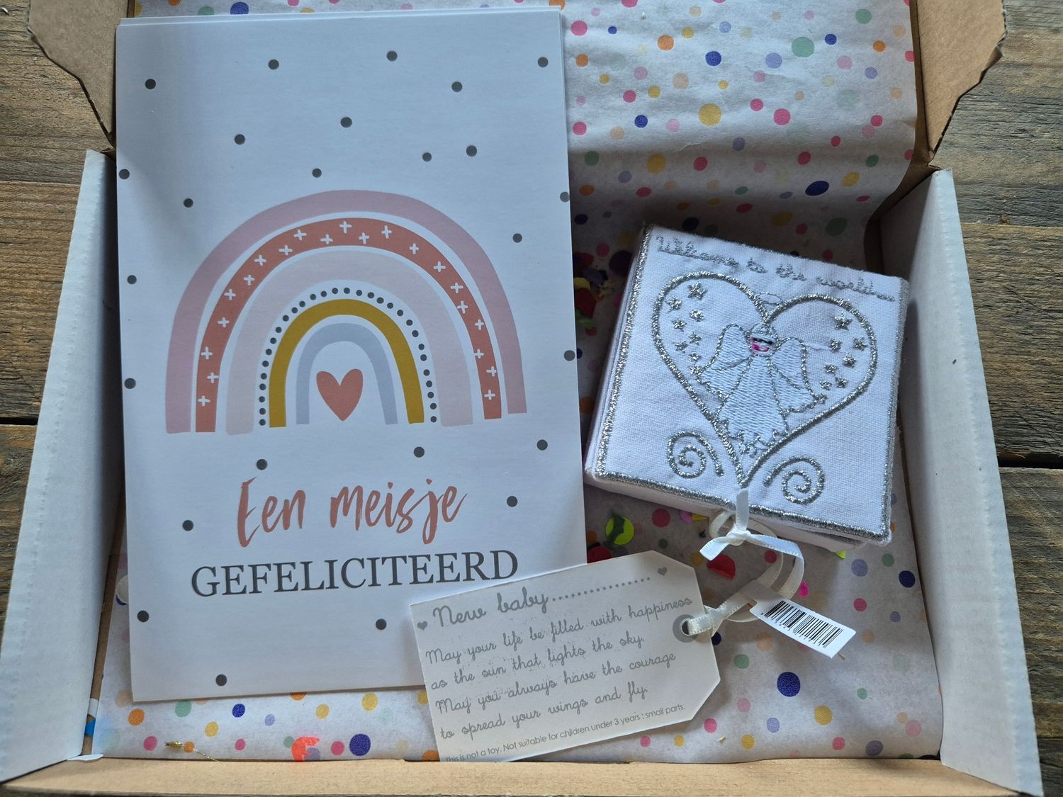 Cadeauverpakking met een regenboogkaart, een hartvormig doosje, een handgeschreven briefje en ingepakte lekkernijen.