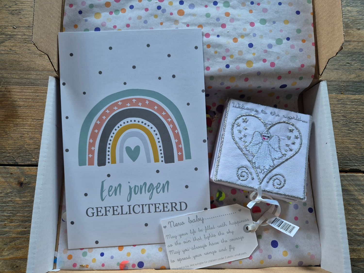 Cadeauverpakking met een regenboogkaart, een hartvormig doosje, een handgeschreven briefje en ingepakte lekkernijen.
