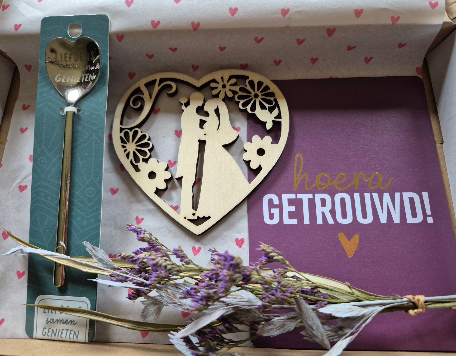 Cadeauverpakking met paarse bloemen, een hartvormig ornament en de tekst