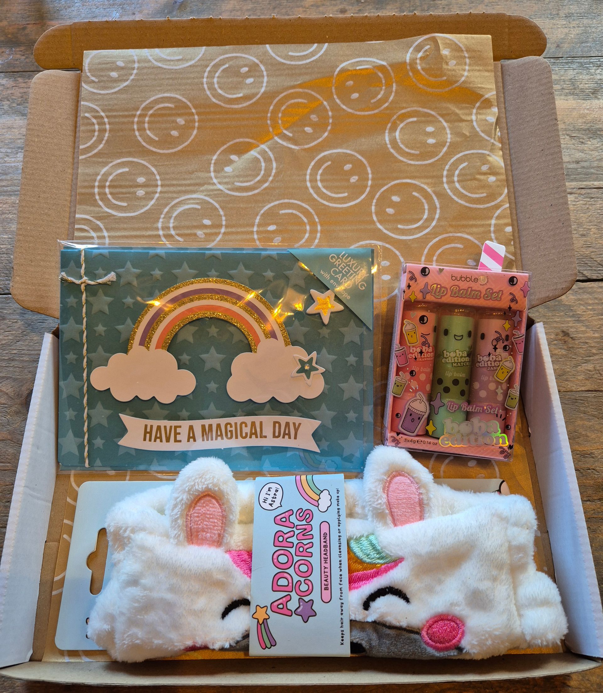 Cadeauverpakking met een eenhoornkaartje, een regenboogkaartje en pluizige witte konijnenslofjes, vastgebonden met een lint.