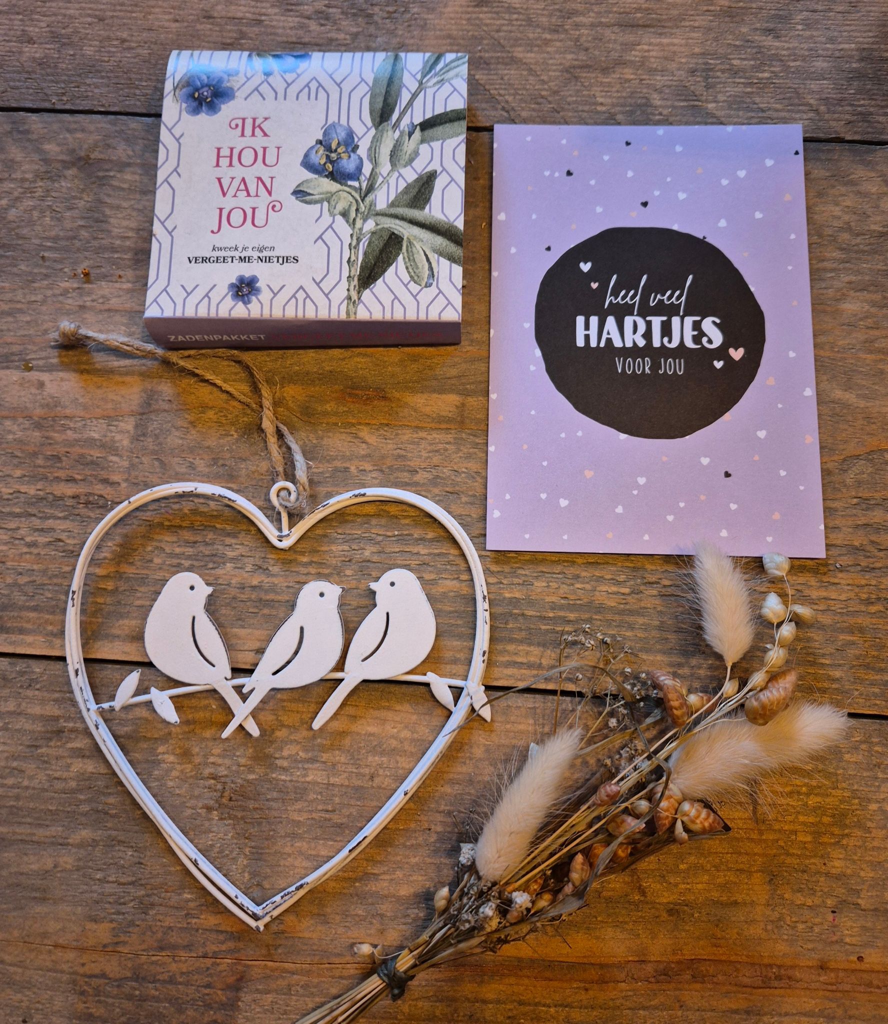 Cadeauverpakking met hartvormige ornamenten, takjes als decoratie en twee wenskaarten op bedrukt papier.