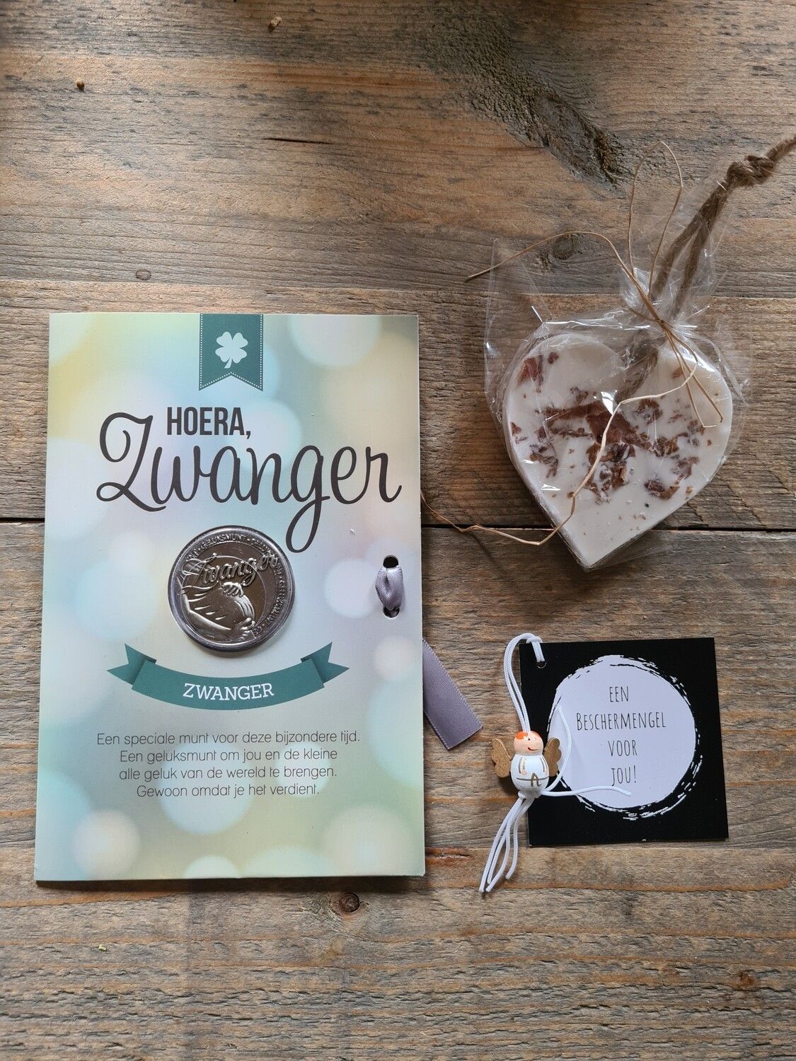 Nederlandse zwangerschapsaankondigingskaart met een munt, een hartje en een klein cadeaulabel op een achtergrond met stippen.