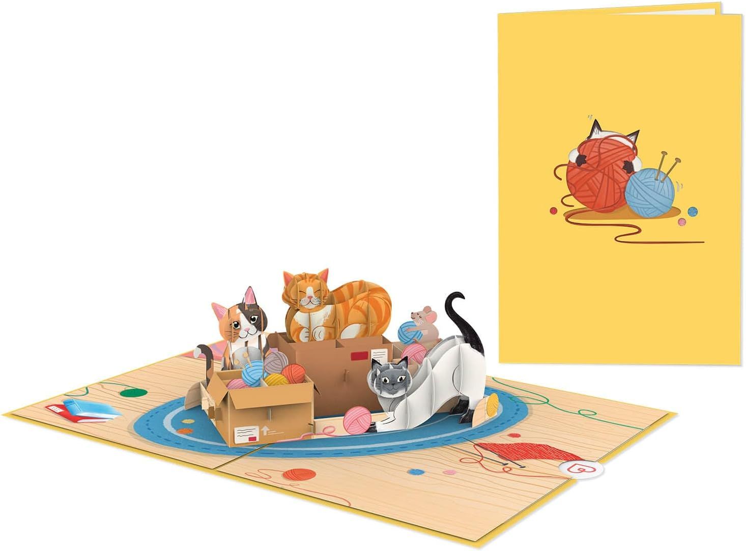 Wenskaart met katten en een muis op een gele omslag, plus kittens en speelgoed op een mat met patroon.
