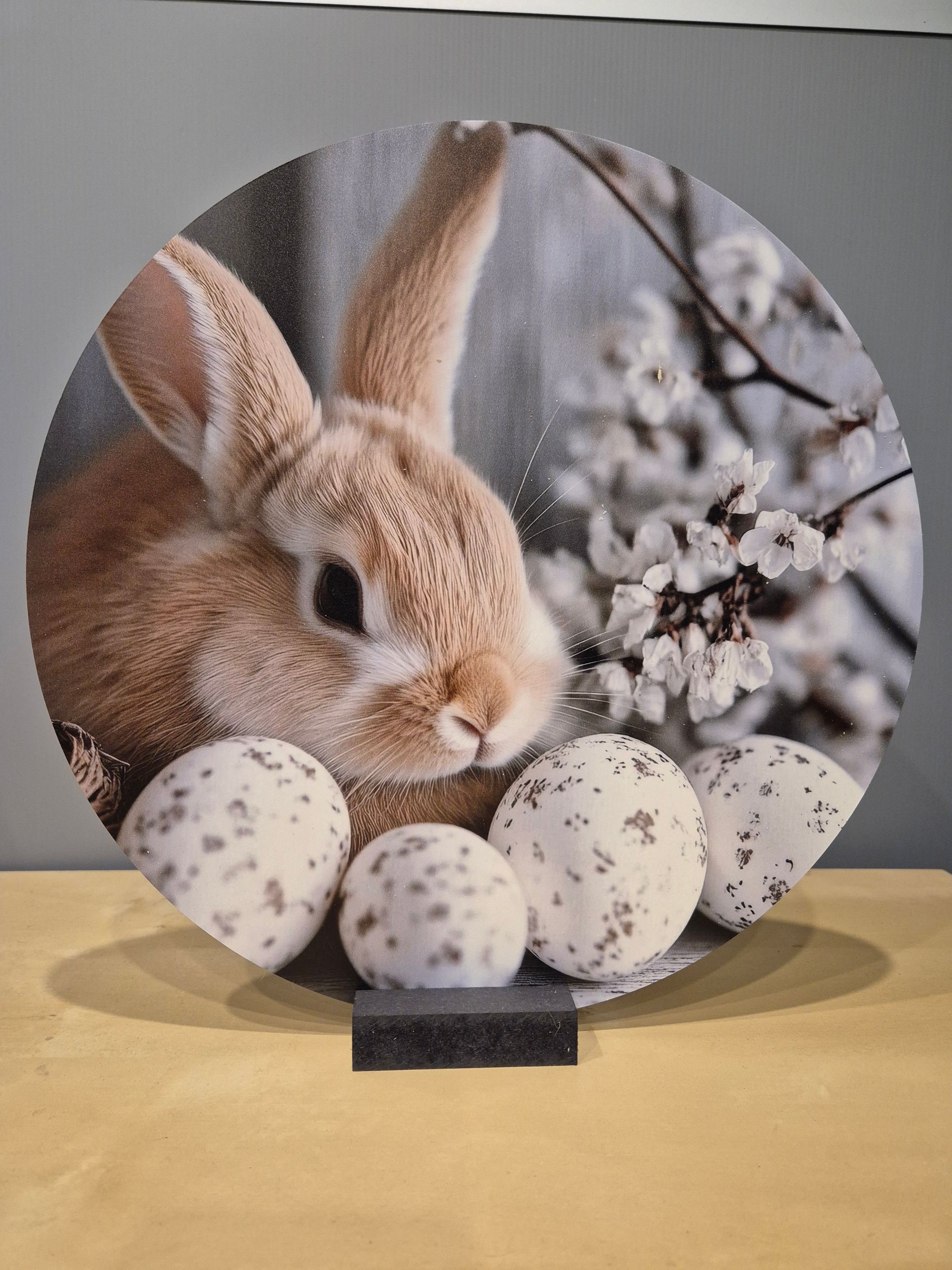 Een schaap afgebeeld op een ronde plaquette, omringd door kleurrijke wilde bloemen.