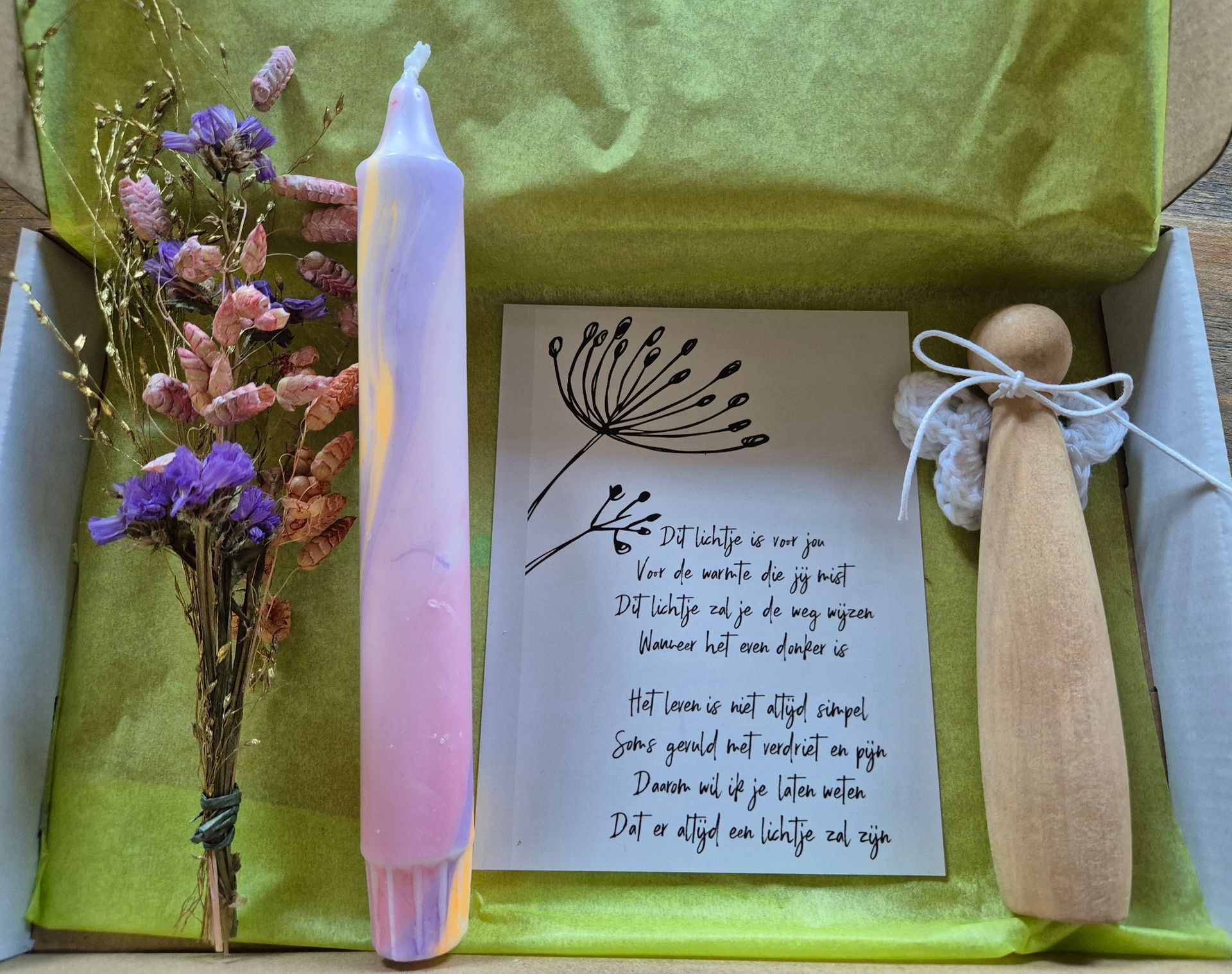 Notitieboekpagina, pastelkleurige kaars, gedroogde bloemen en houten pop op een rustieke houten ondergrond.
