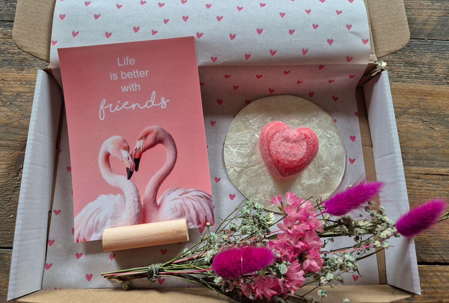 Cadeauverpakking met een kaartje met een roze flamingo, een hartvormig zeepje en gedroogde roze bloemen, met een briefje met de tekst