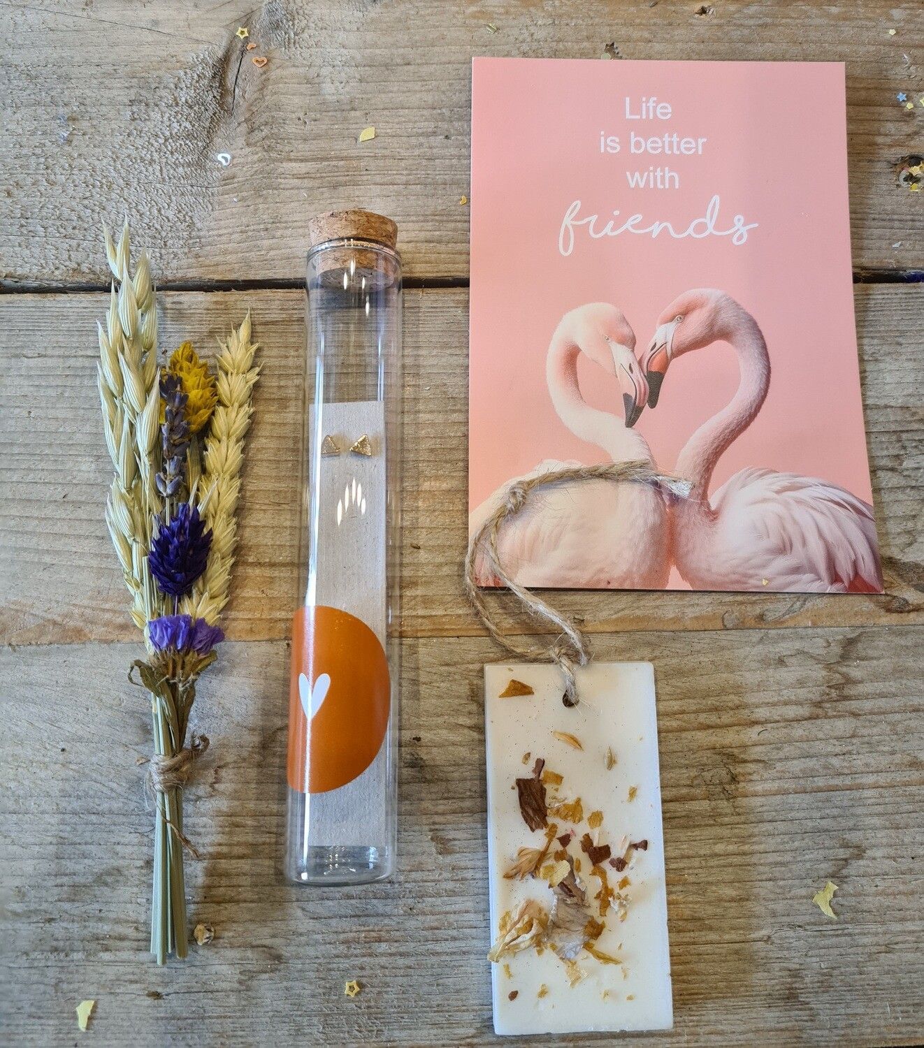 Roze flamingo notitieboekje, oranje reageerbuisje met wit hartje, gedroogde bloemen en een botanische kaart op een stoffen ondergrond met stippen