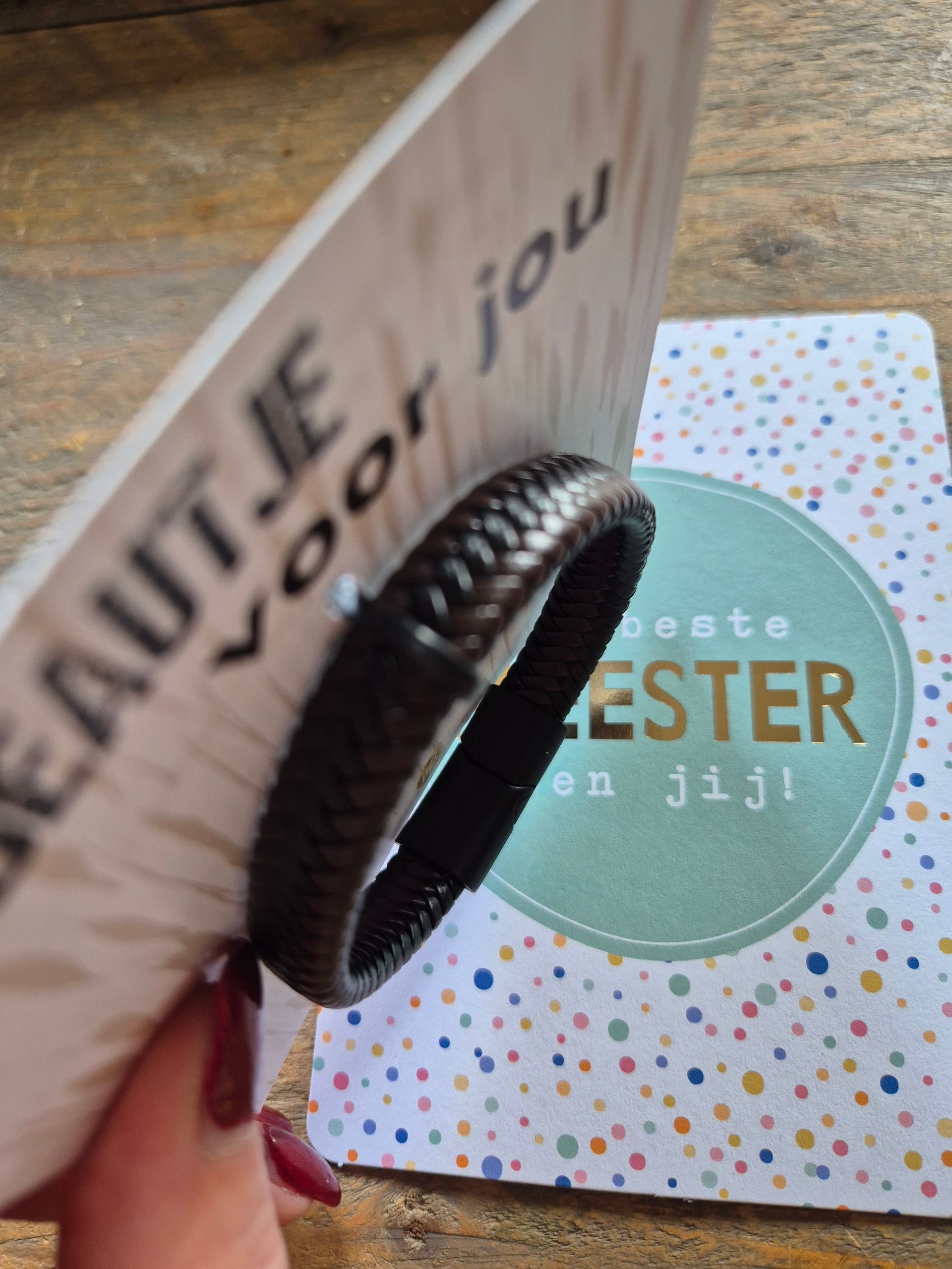 Bracelet beside two Dutch gift cards on a wooden surface, one reading “cadeautje voor jou” and “De beste meester ben jij!”