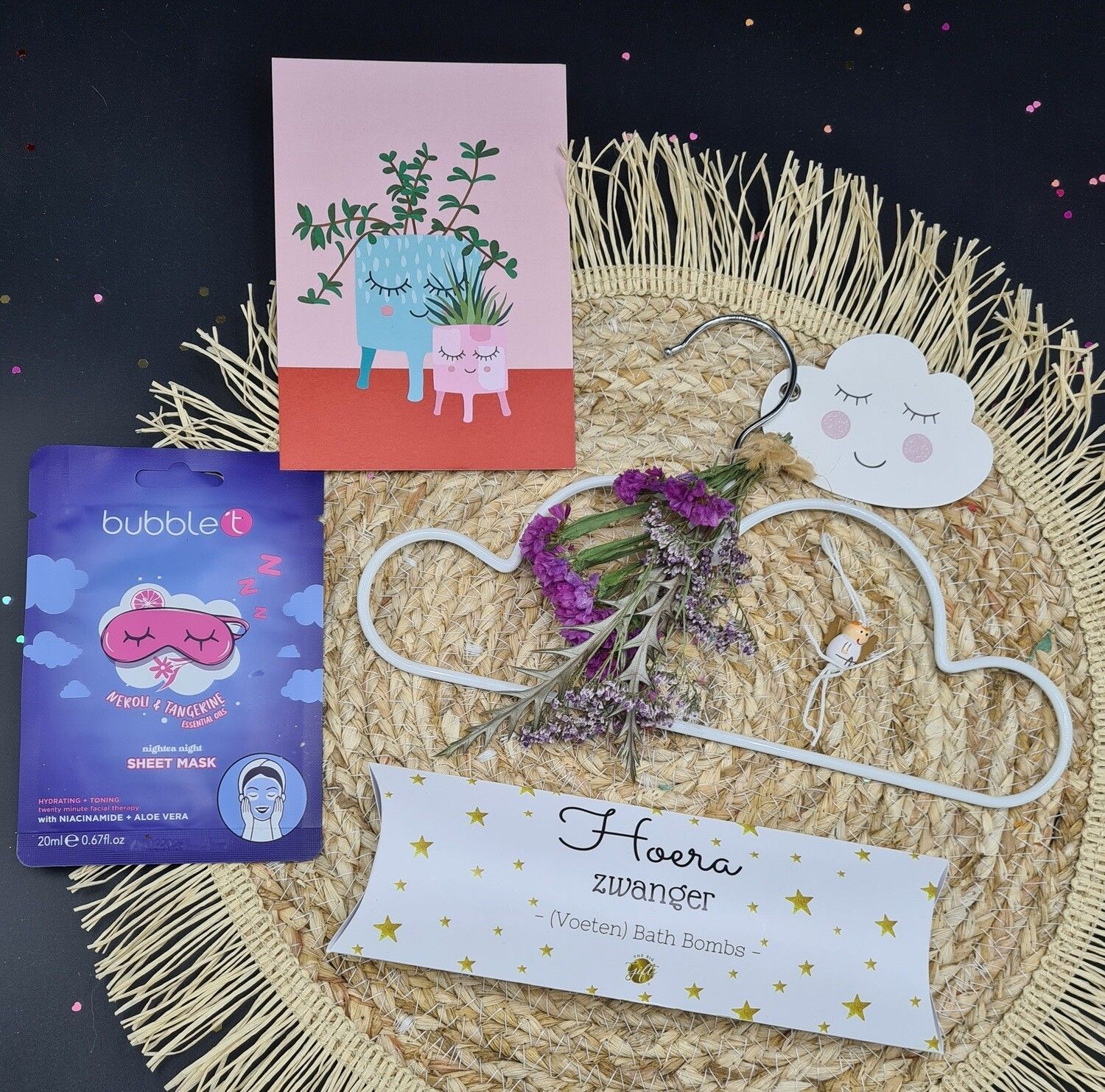 Cadeauverpakking met briefpapier, kaarten en bloemen in roze wolkjesthema op een bruine ondergrond.