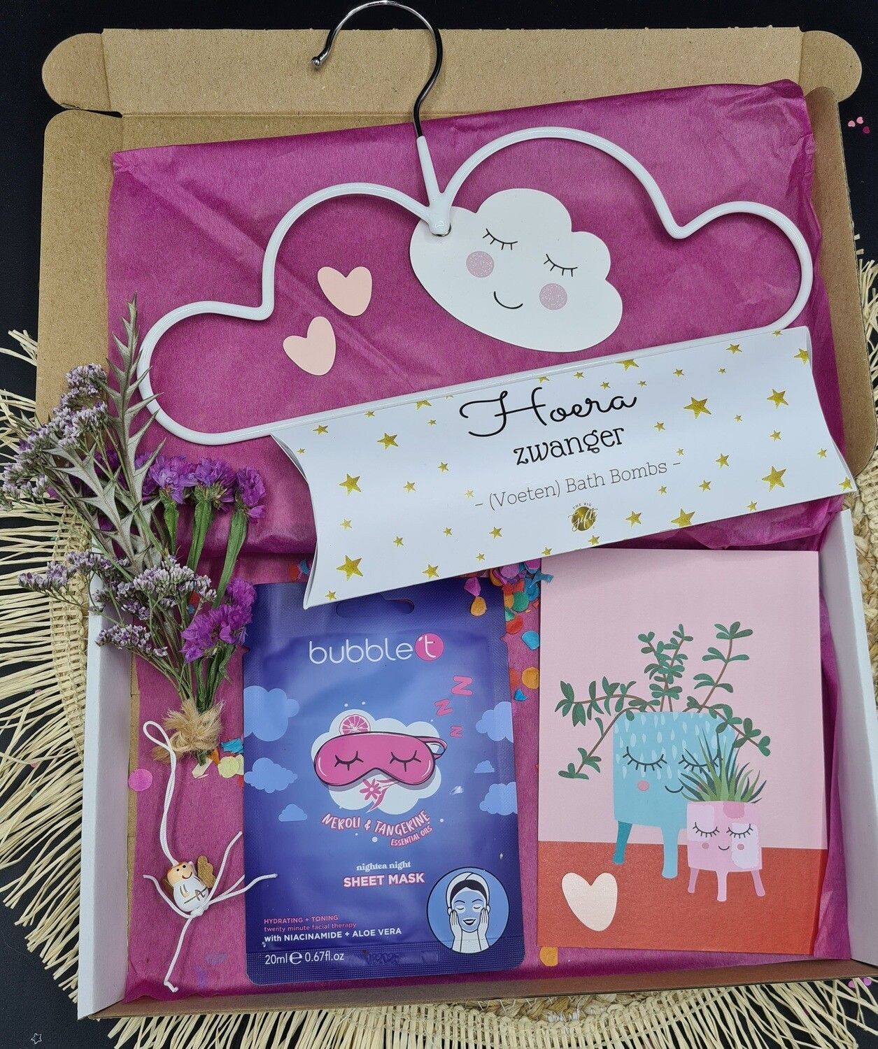 Cadeauverpakking met briefpapier, kaarten en bloemen in roze wolkjesthema op een bruine ondergrond.
