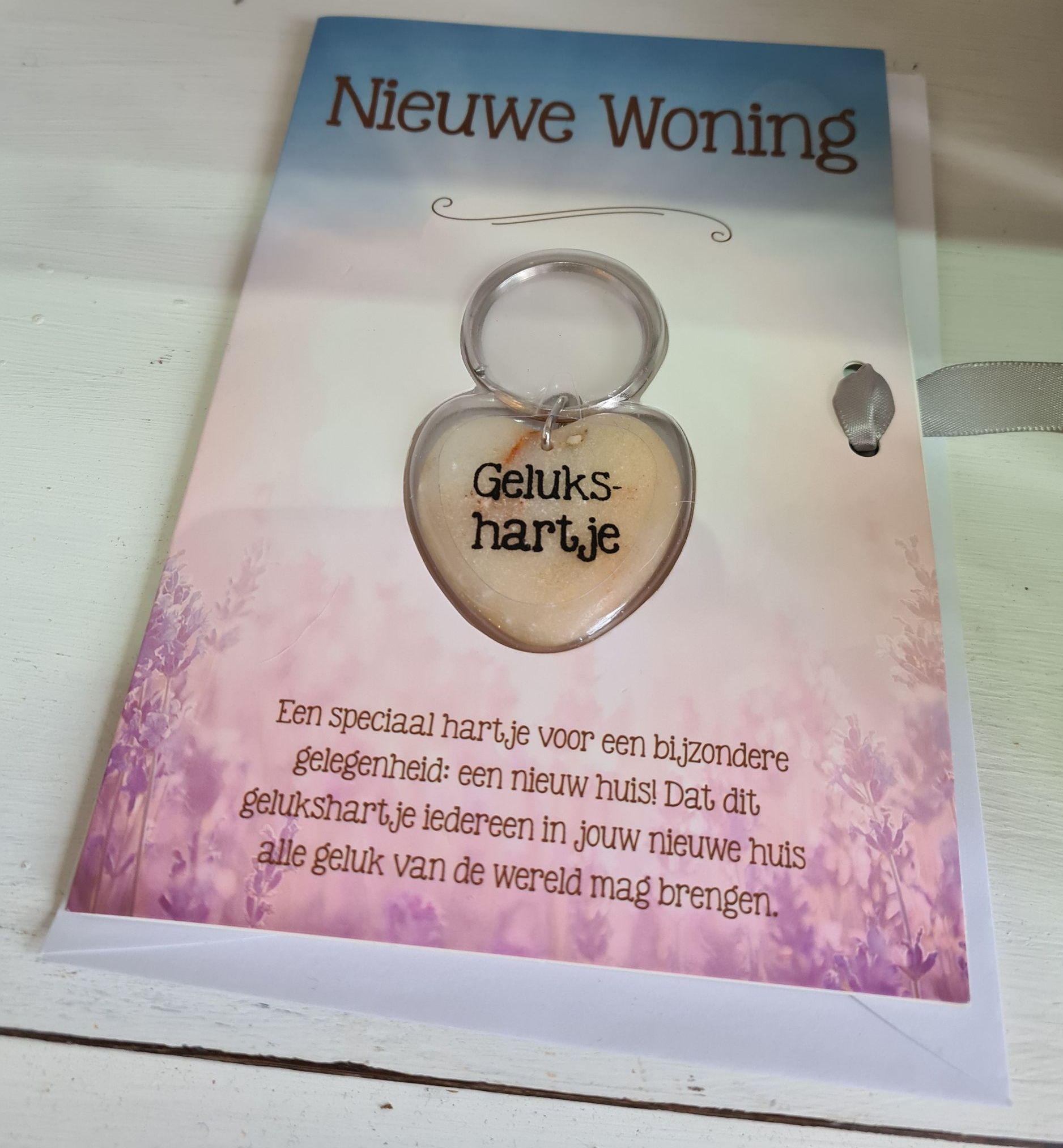 Miniatuurhuisje met rood dak op een groene sokkel, naast een bijpassend groen boekje.