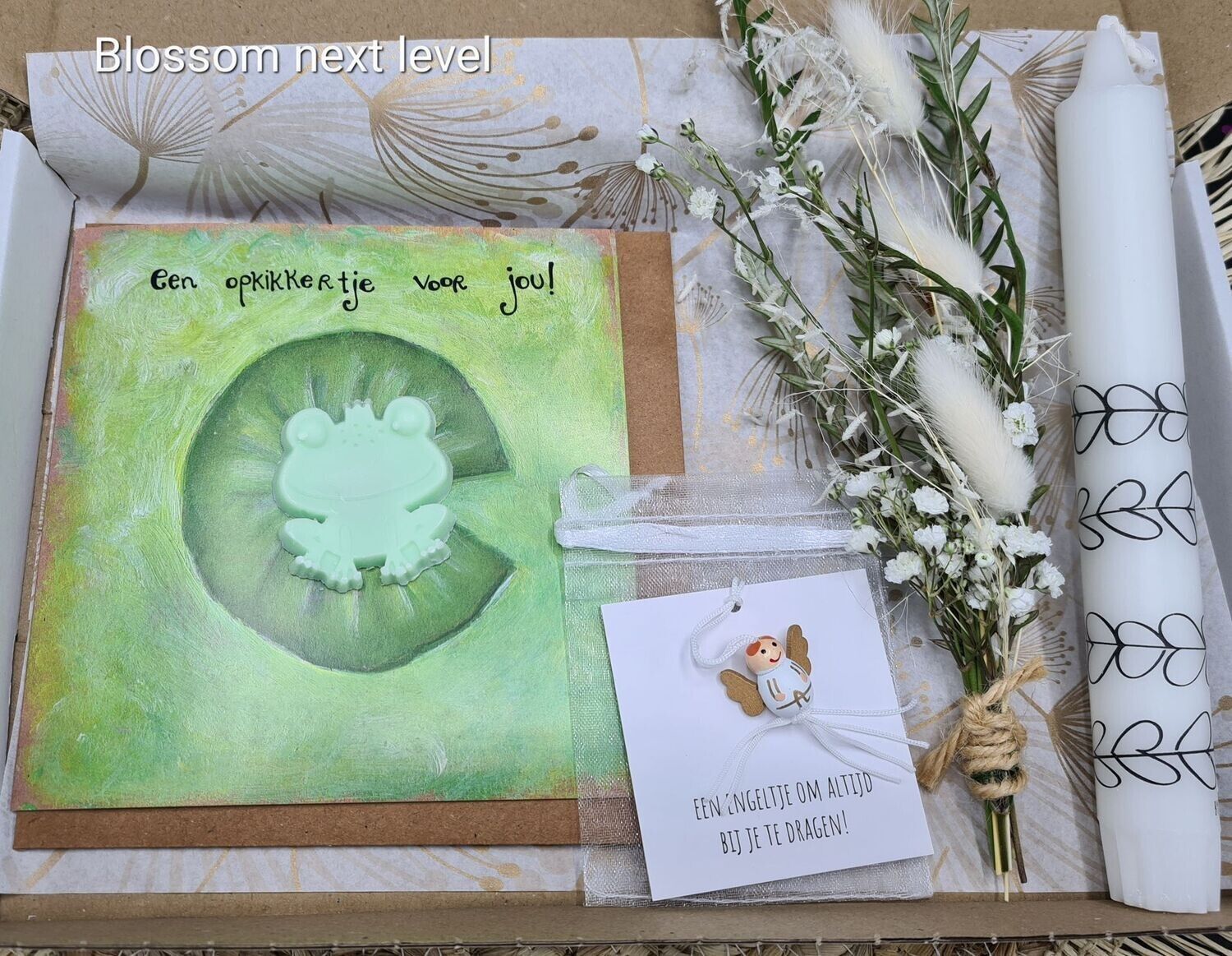 Groene cadeauset met bloemenmotief, inclusief kaart, gedroogde bloemen en opgerold papier op een tafel.