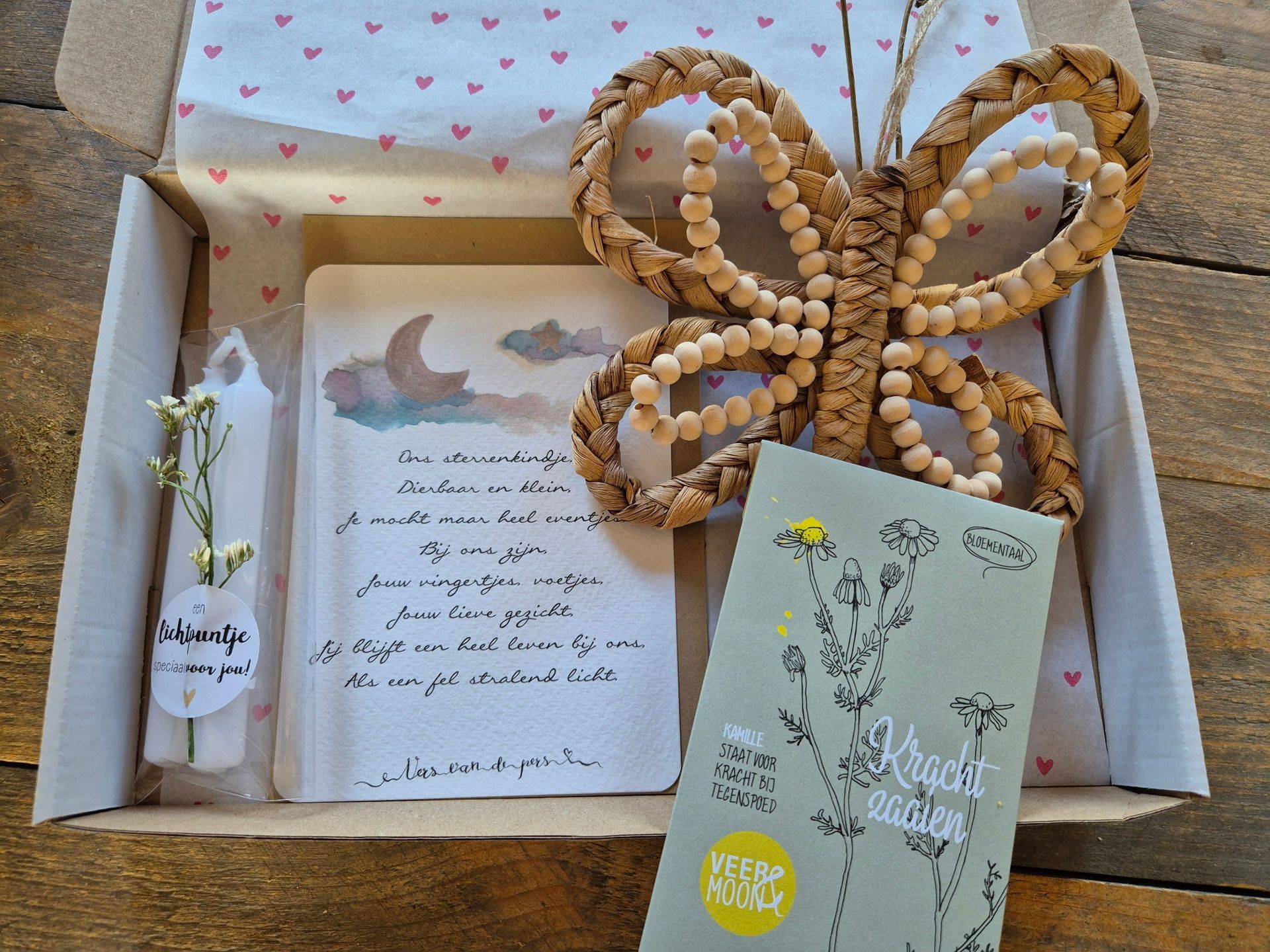 Cadeauverpakking met een bloemetje, een witte kaars, een vlinderdecoratie van kralen en een klein kaartje op roze vloeipapier.