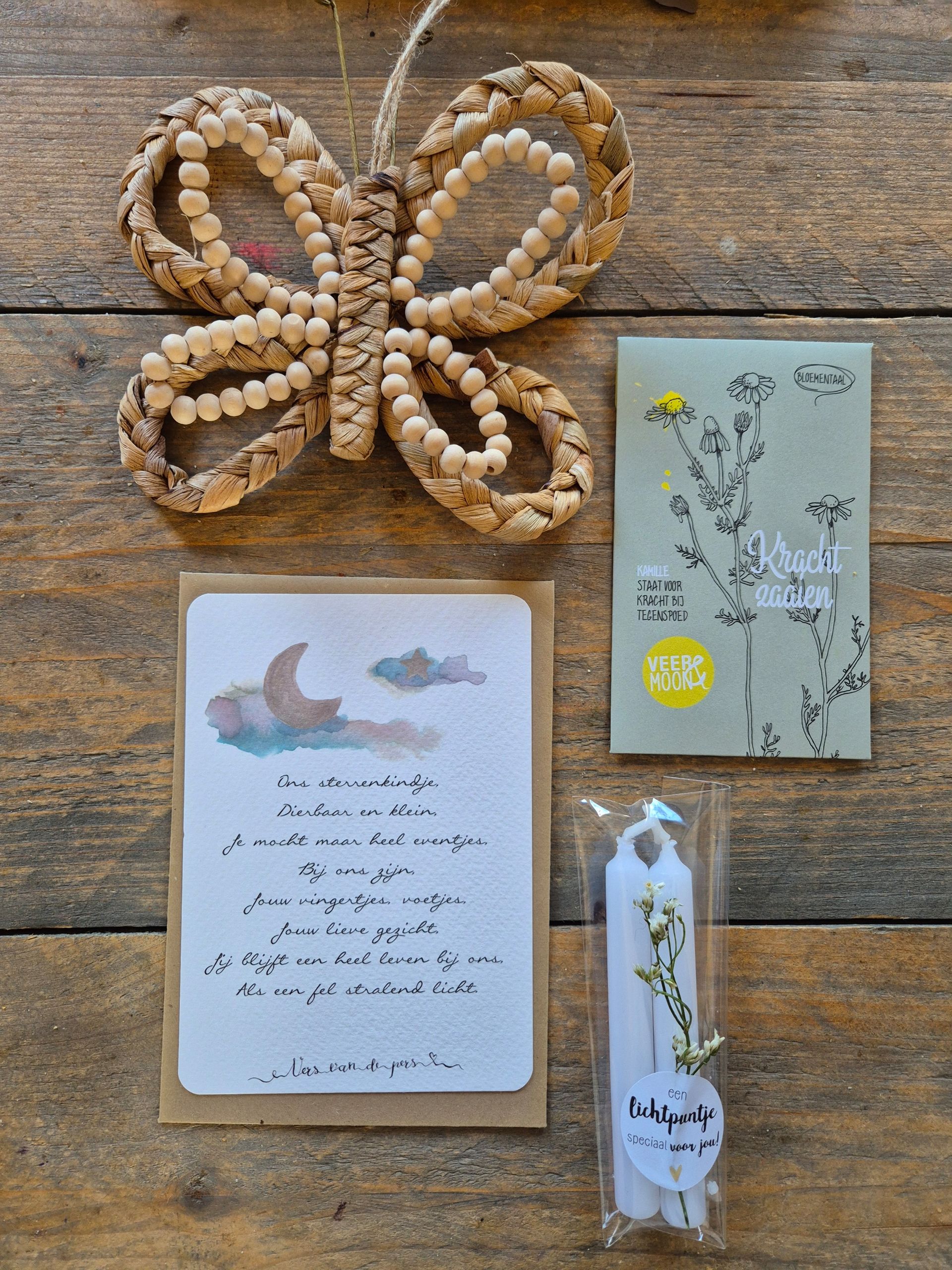 Cadeauverpakking met een bloemetje, een witte kaars, een vlinderdecoratie van kralen en een klein kaartje op roze vloeipapier.