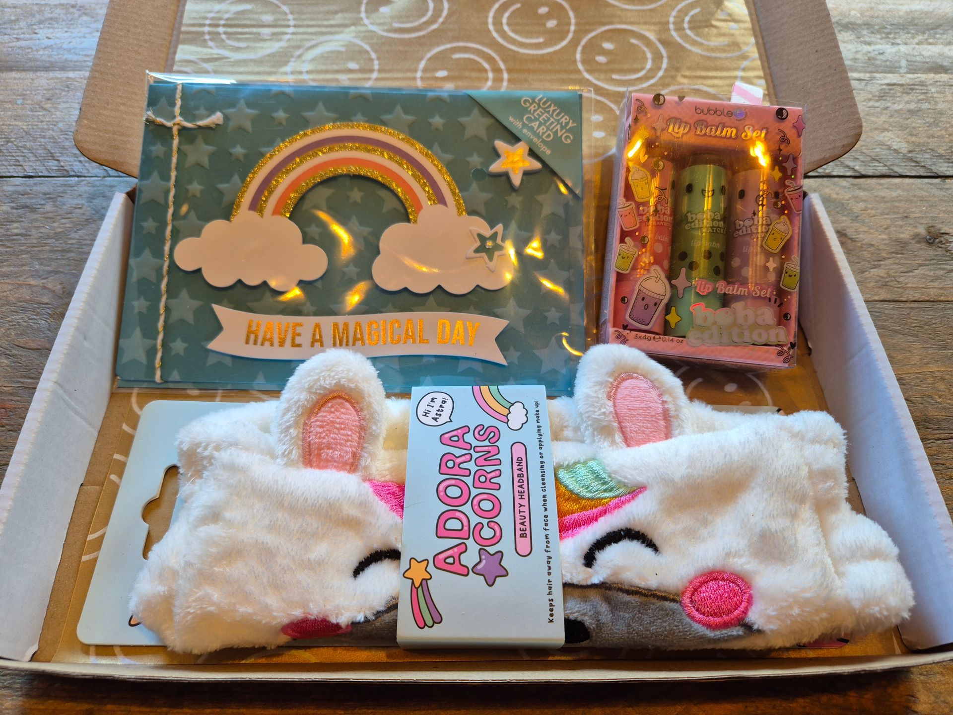 Cadeauverpakking met een eenhoornkaartje, een regenboogkaartje en pluizige witte konijnenslofjes, vastgebonden met een lint.