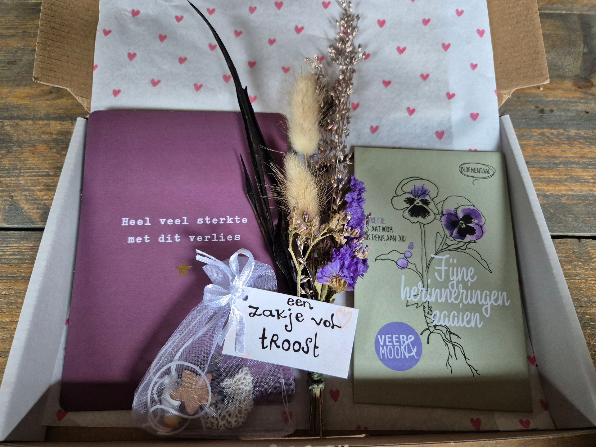 Cadeauverpakking met bloemen en een handgeschreven briefje in roze en groene notitieboekjes.