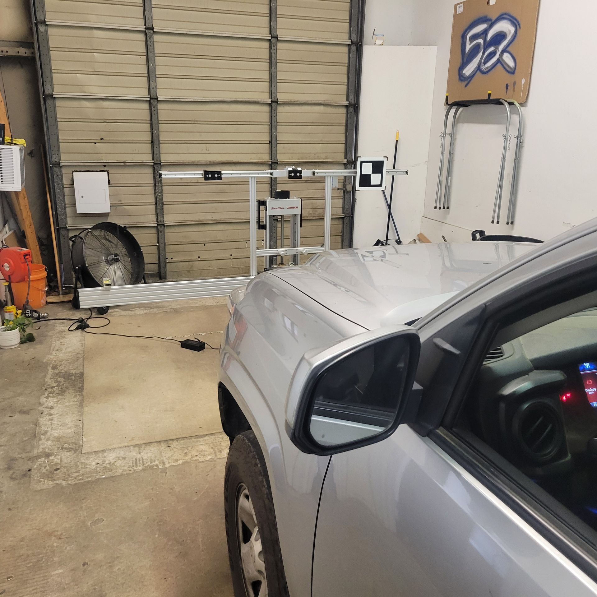 A silver car is parked in a garage with a cardboard sign