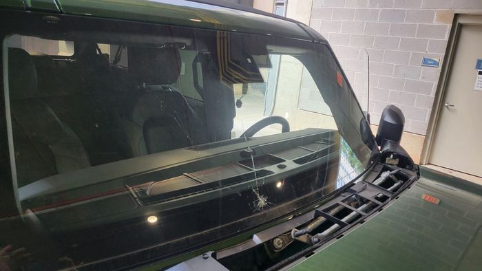 A green van with a broken windshield is parked in a garage