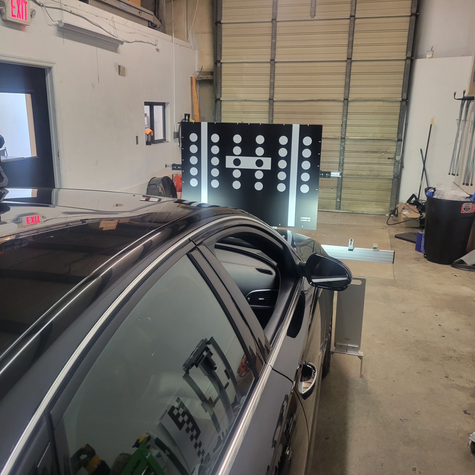 A car is sitting in a garage next to a red exit sign