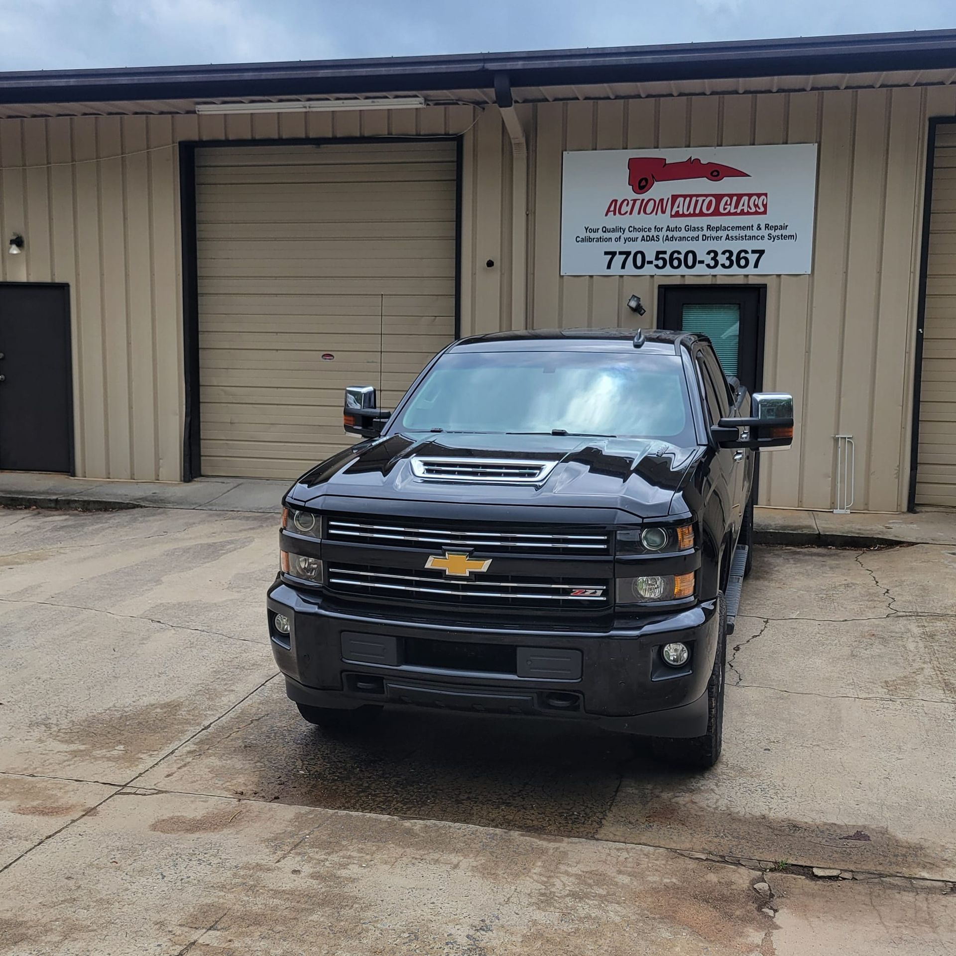 A black truck is parked in front of a building