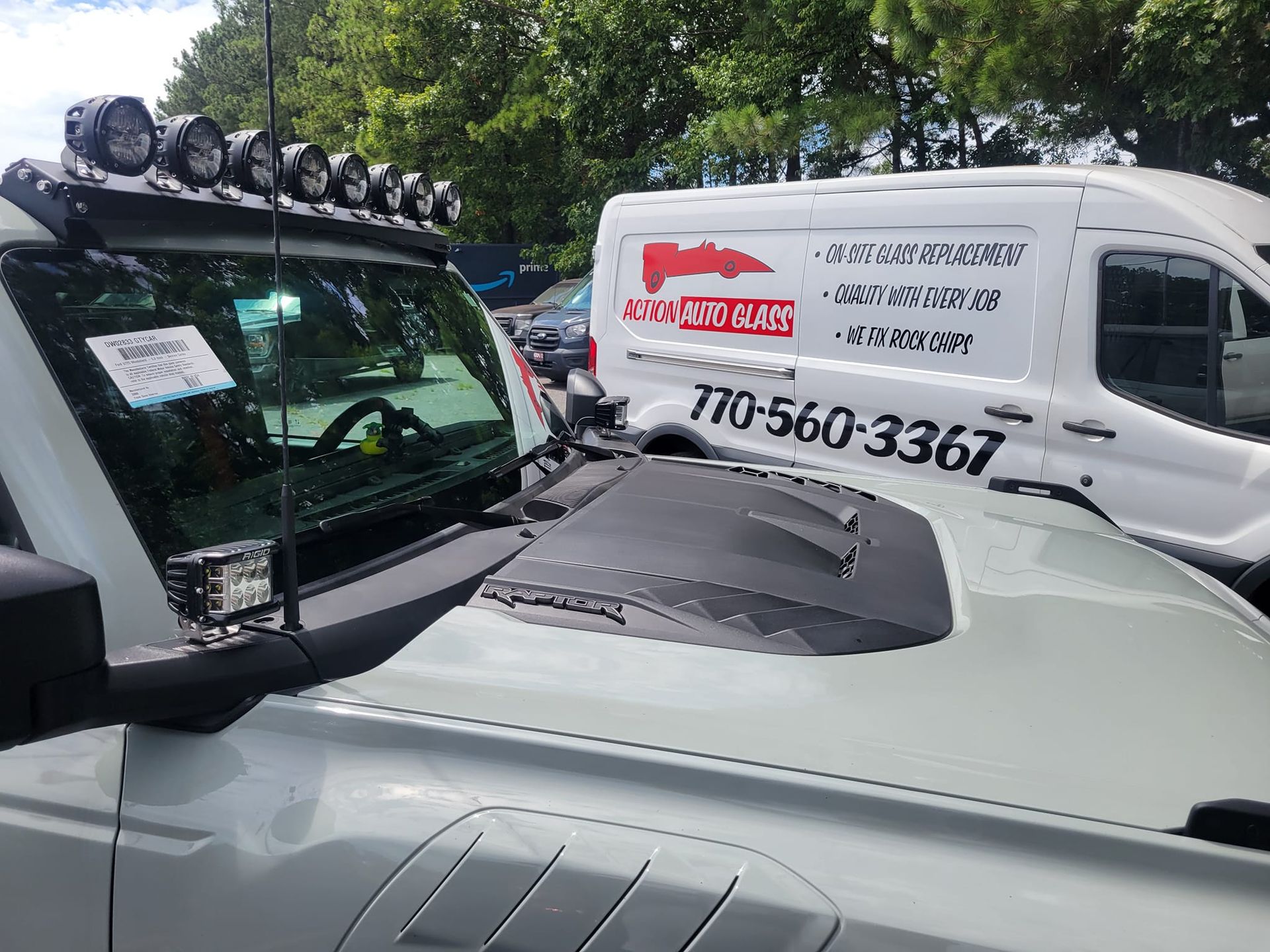 A white truck is parked next to a white van