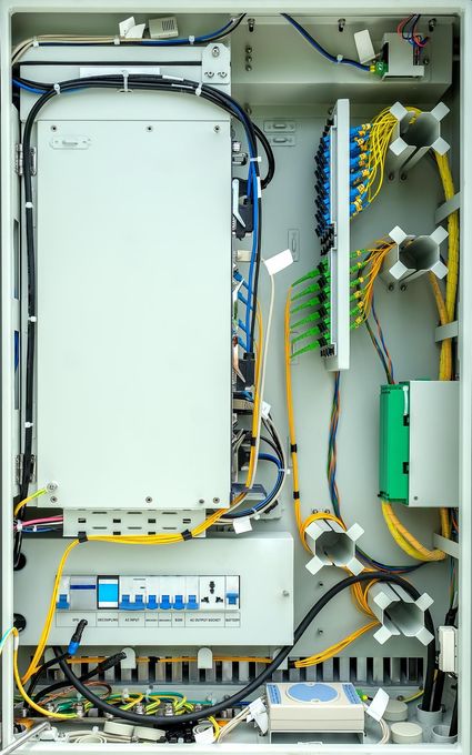 The inside of a electrical box with a lot of wires coming out of it.